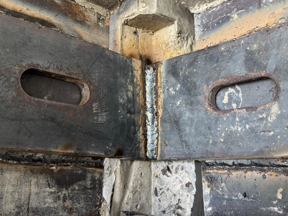 Stitch plates welded across a precast panel corner connection